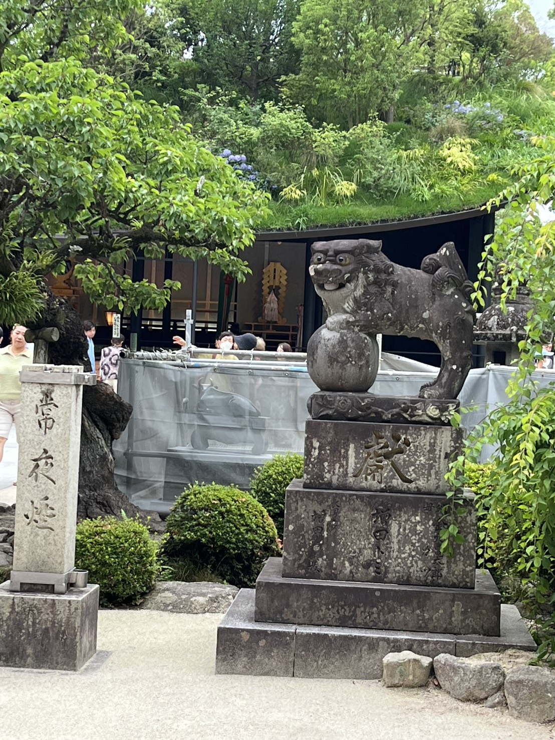 緑の木々を背に鎮座する狛犬の石像
