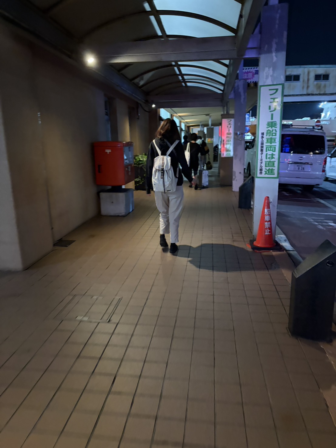 夜のフェリーターミナルへと続く歩道を歩く様子