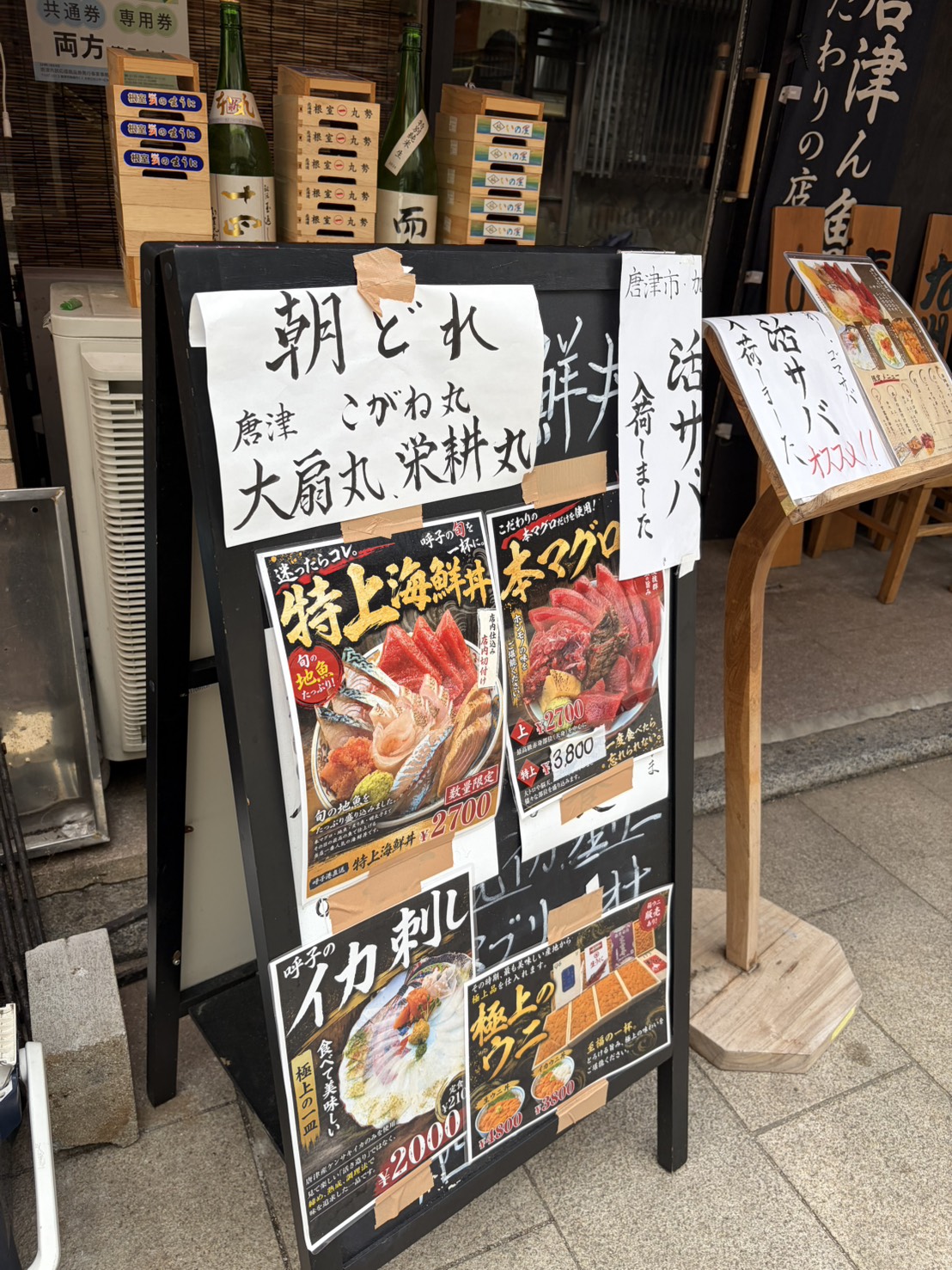 店頭に置かれた海鮮丼やイカ刺しのメニュー看板