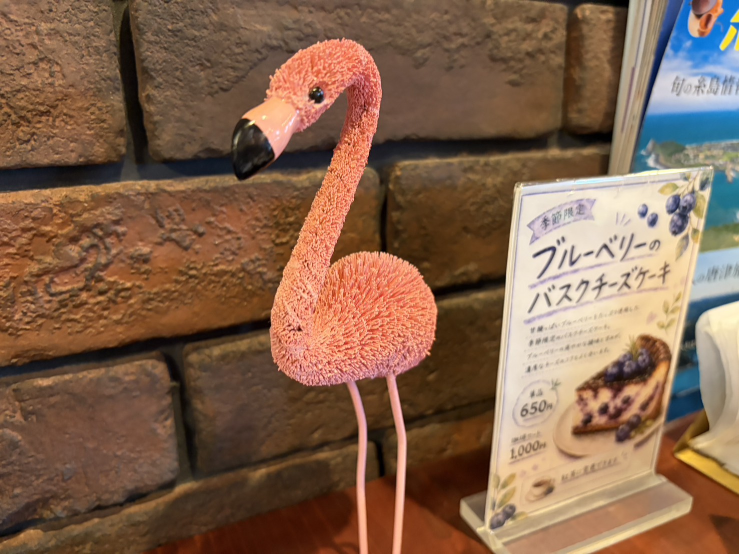 レンガ壁の前に飾られた可愛らしいフラミンゴの置物