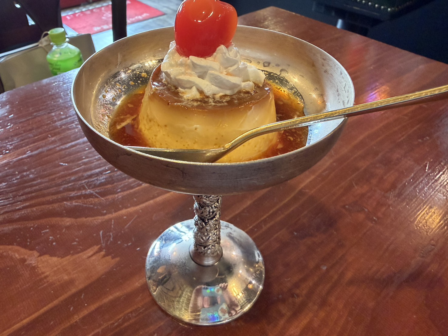 銀の器に盛られた生クリームとチェリー付きの固めプリン