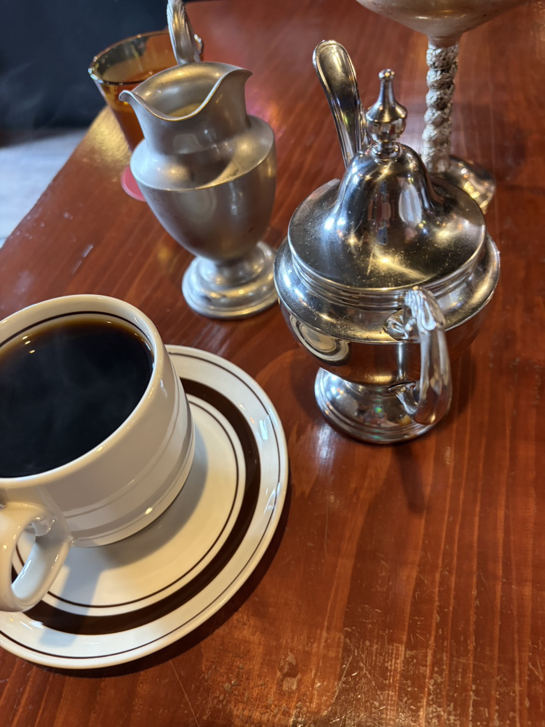 ホットコーヒーと銀色のアンティークなミルクピッチャー