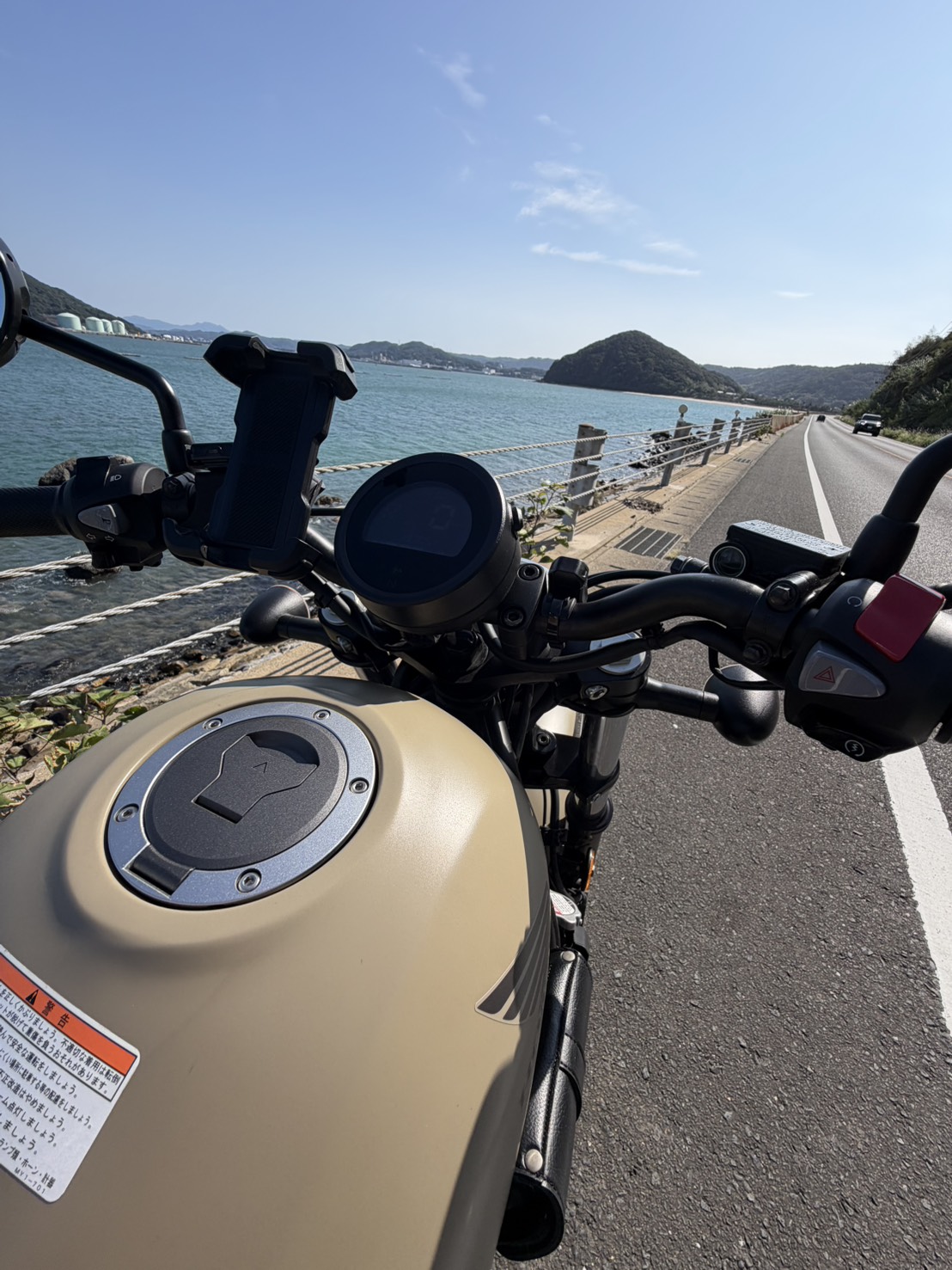バイクのハンドル越しに広がる青い海と道路