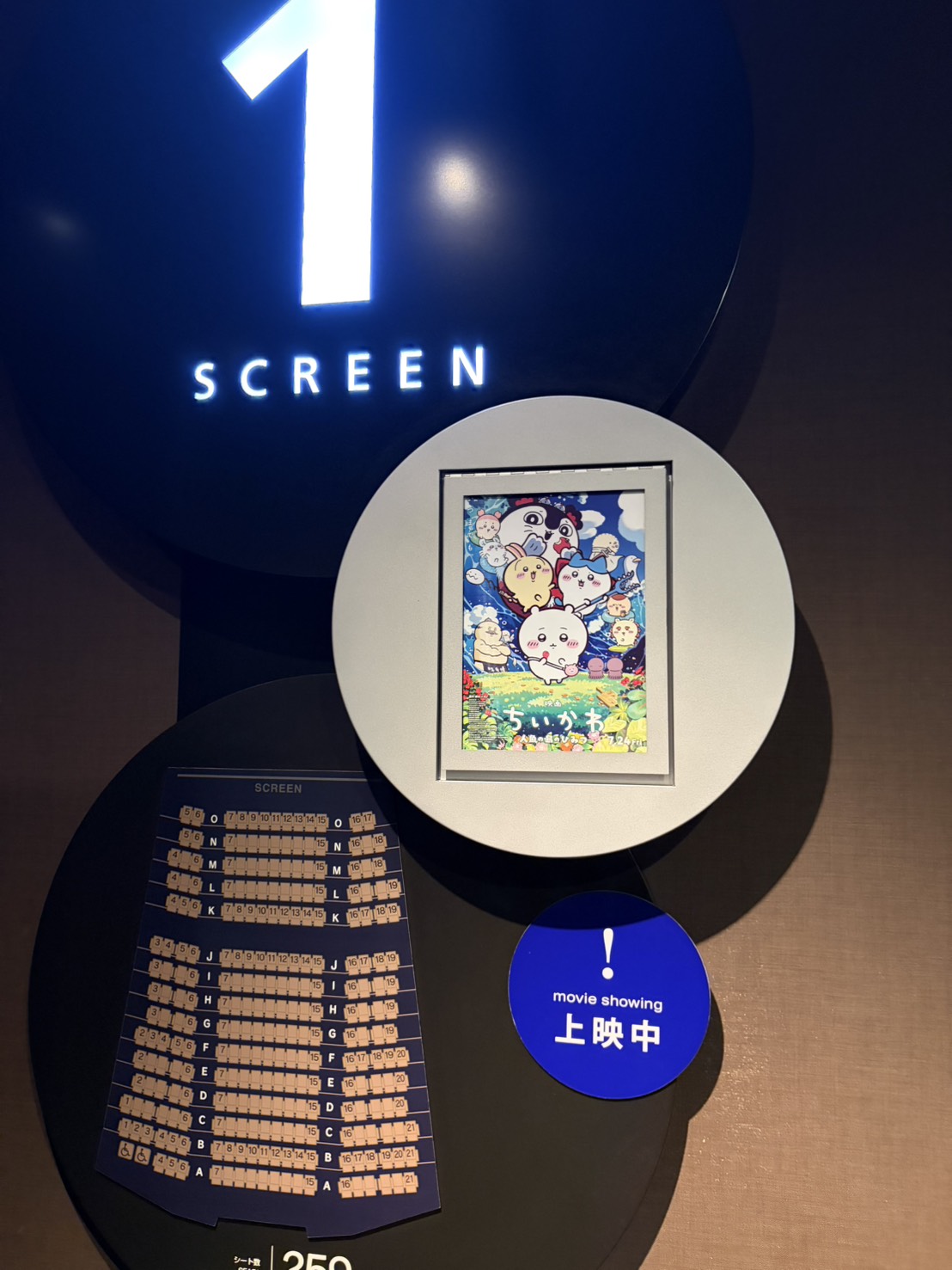 スクリーン1の入り口に飾られた映画の座席表と案内板